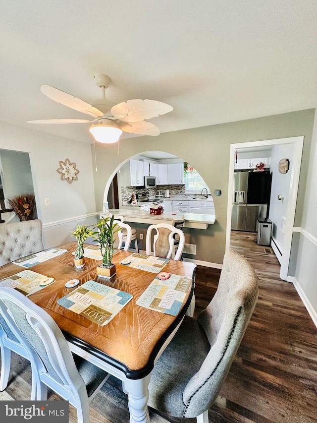 dining room featuring ceiling fan, sink, and dark wood-type flooring