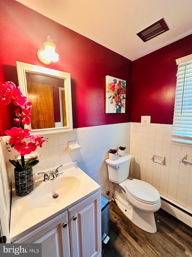 bathroom featuring vanity, a baseboard heating unit, toilet, tile walls, and wood-type flooring