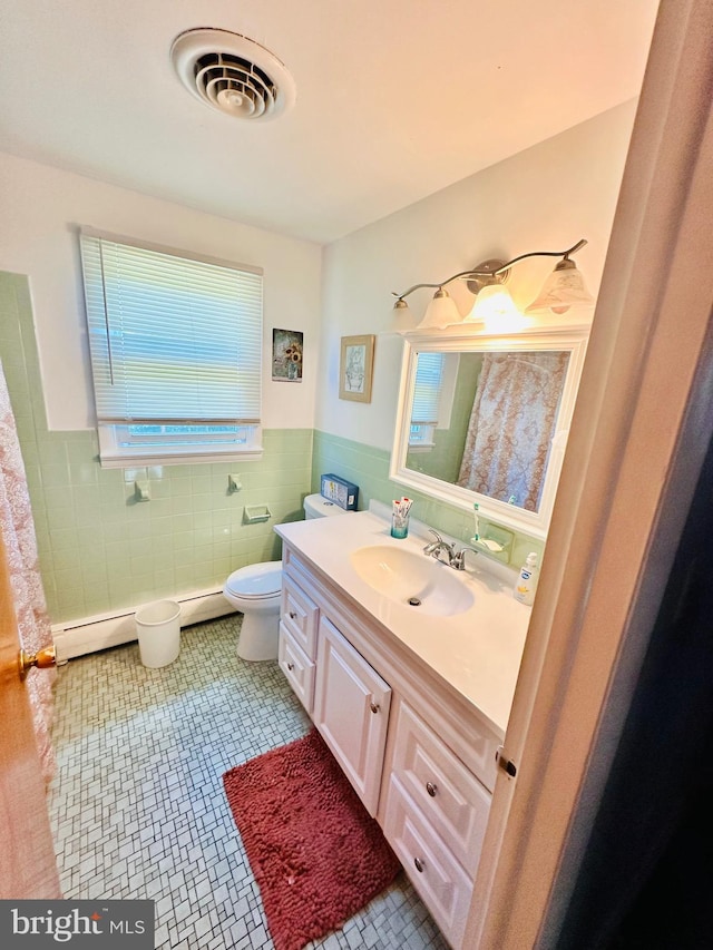 bathroom with vanity, tile patterned flooring, toilet, tile walls, and a baseboard radiator