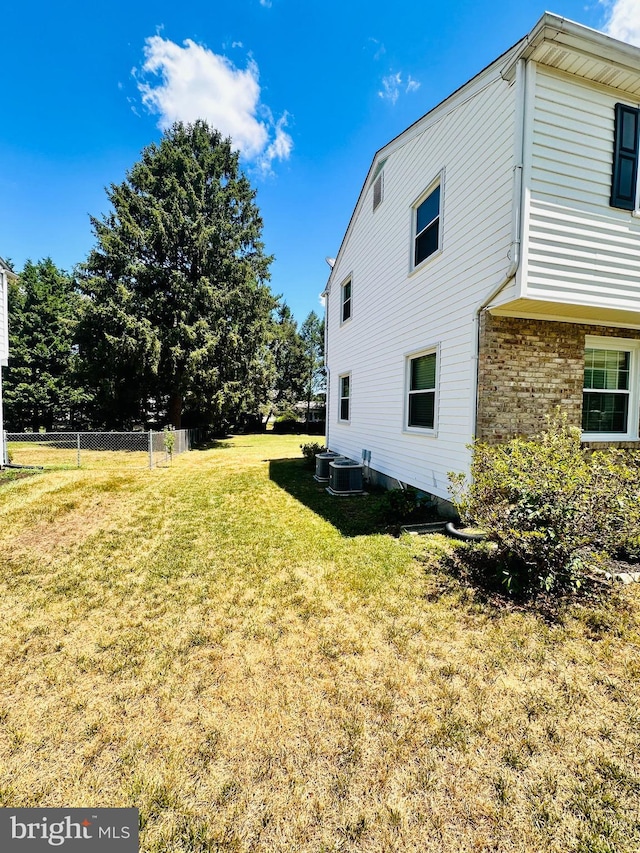 view of side of property with a yard and central air condition unit