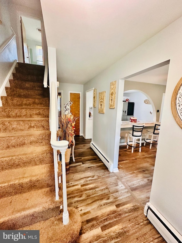 stairs featuring hardwood / wood-style floors and a baseboard radiator