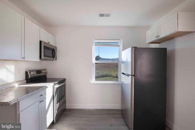 kitchen featuring white cabinetry, appliances with stainless steel finishes, and light hardwood / wood-style flooring