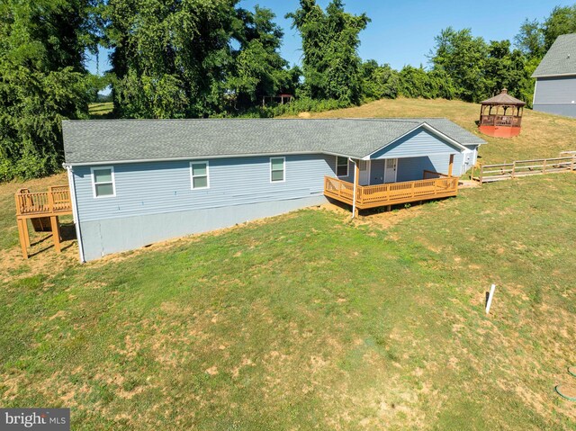 back of property featuring a gazebo, a wooden deck, and a lawn