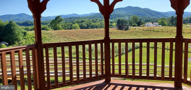 wooden deck featuring a mountain view and a yard