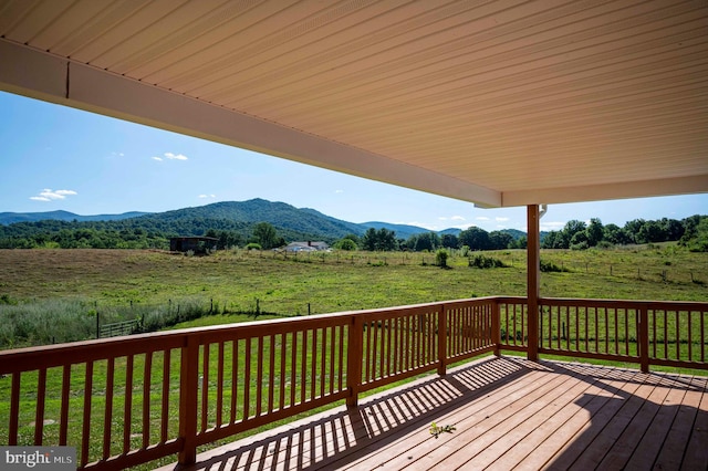 wooden terrace featuring a lawn, a mountain view, and a rural view