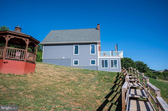 back of house with a gazebo, a balcony, and a lawn