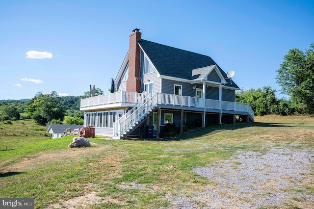 back of property with a wooden deck and a lawn