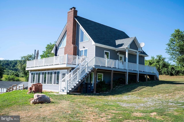 rear view of property with a sunroom, a yard, and a deck