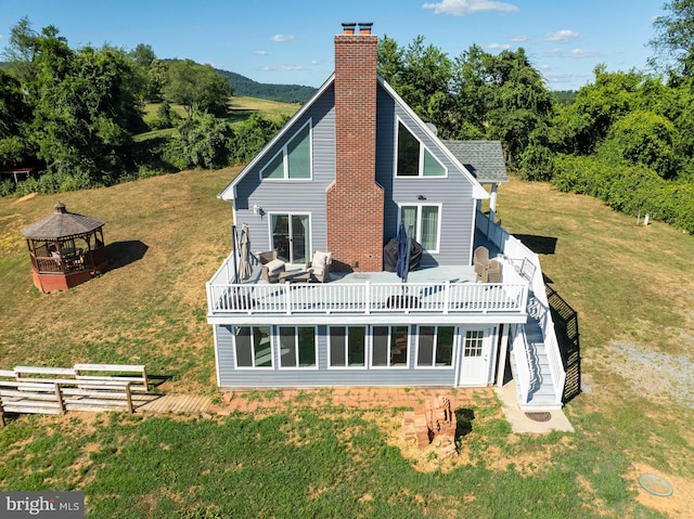 back of property with a gazebo, a sunroom, a deck, and a lawn