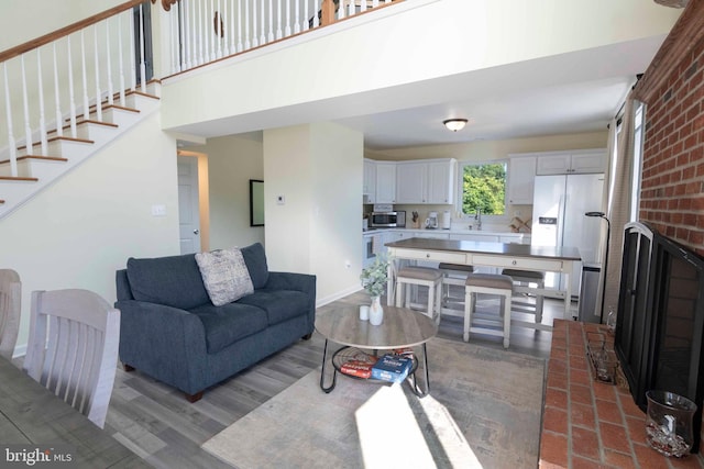 living room featuring wood-type flooring, a brick fireplace, and sink