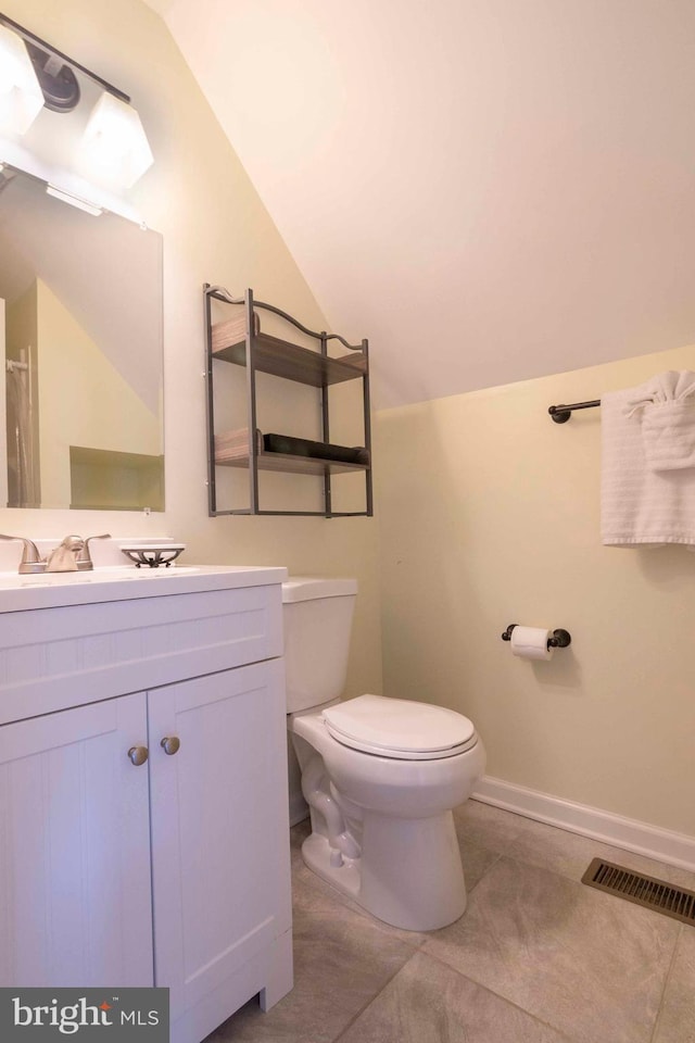 bathroom with toilet, vanity, and vaulted ceiling