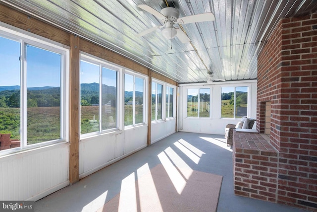 unfurnished sunroom with a mountain view, ceiling fan, and wooden ceiling