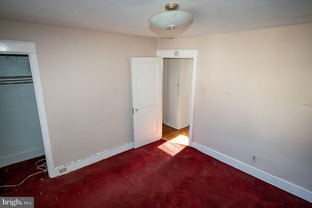 unfurnished bedroom featuring dark colored carpet and a closet