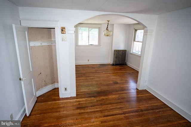 interior space with radiator, dark hardwood / wood-style floors, an inviting chandelier, and plenty of natural light