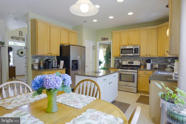 kitchen with a center island, backsplash, dark stone counters, light wood-type flooring, and stainless steel appliances