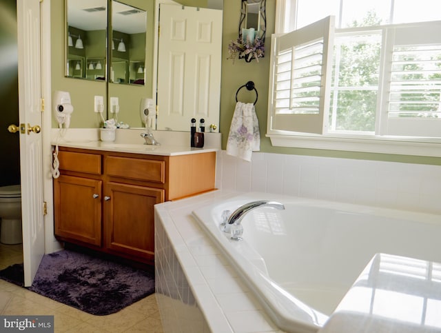 bathroom with tile patterned flooring, vanity, toilet, and tiled bath