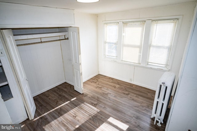 unfurnished bedroom with radiator heating unit, light wood-type flooring, and a closet