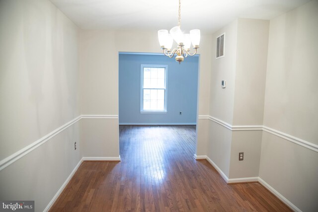 unfurnished dining area featuring dark hardwood / wood-style floors and an inviting chandelier