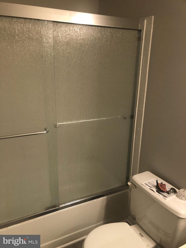 bathroom with toilet and enclosed tub / shower combo