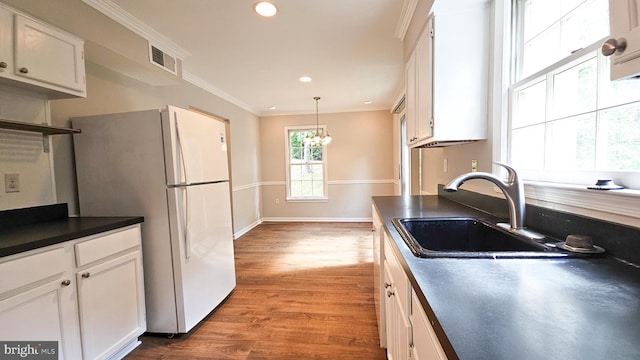 kitchen featuring white cabinets, sink, light hardwood / wood-style floors, a notable chandelier, and white fridge