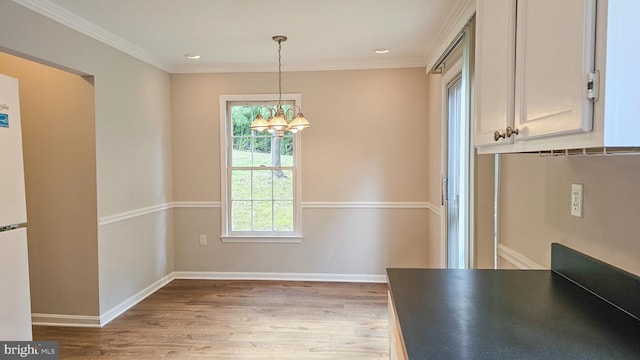 unfurnished dining area featuring light hardwood / wood-style floors, crown molding, and a chandelier