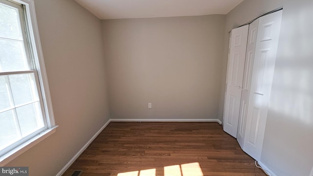 unfurnished bedroom with multiple windows and dark wood-type flooring