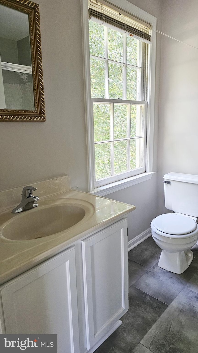 bathroom featuring a shower with door, vanity, a healthy amount of sunlight, and toilet