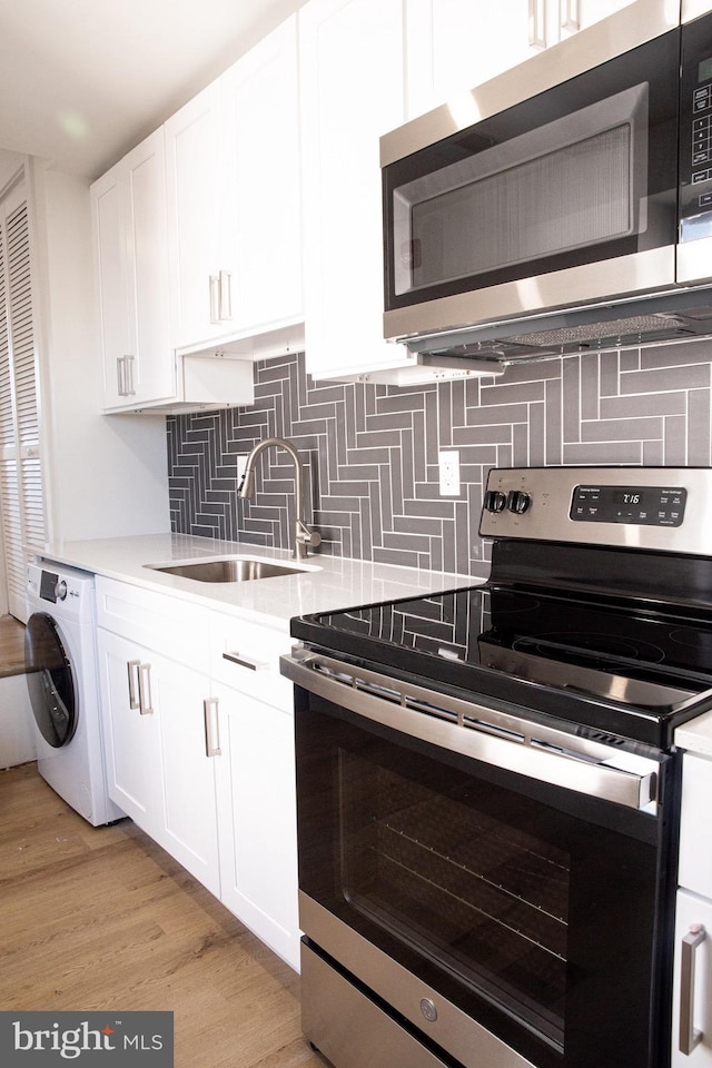 kitchen featuring washer / clothes dryer, sink, white cabinets, and stainless steel appliances