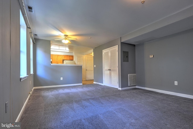 unfurnished living room with ceiling fan, dark carpet, and electric panel