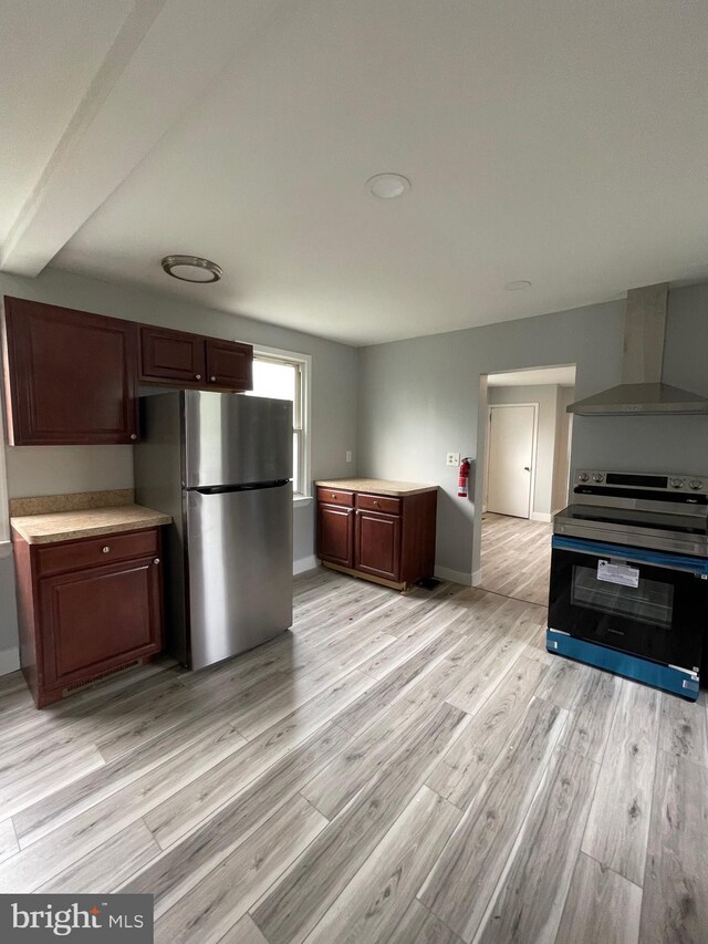 kitchen featuring range with electric stovetop, stainless steel refrigerator, light hardwood / wood-style flooring, and wall chimney exhaust hood