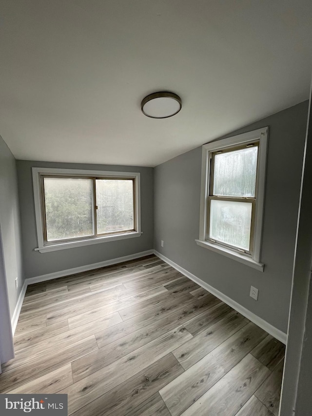 unfurnished room featuring lofted ceiling and light wood-type flooring