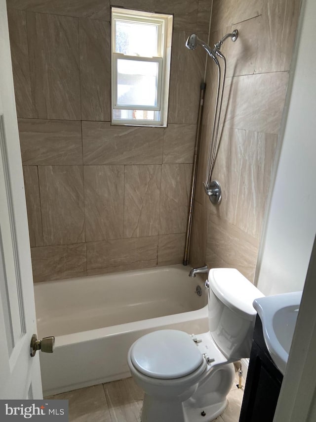 full bathroom featuring vanity, tiled shower / bath combo, and toilet