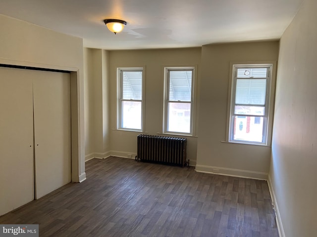 unfurnished bedroom featuring dark hardwood / wood-style flooring, a closet, and radiator heating unit