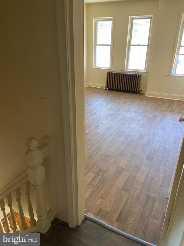 empty room with dark hardwood / wood-style flooring and radiator heating unit