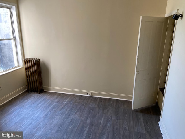 empty room with dark hardwood / wood-style floors and radiator