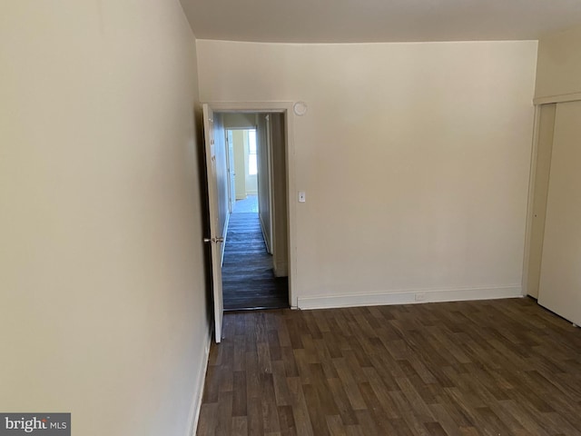 unfurnished room with dark wood-type flooring