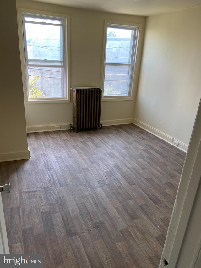 spare room with radiator and dark hardwood / wood-style floors