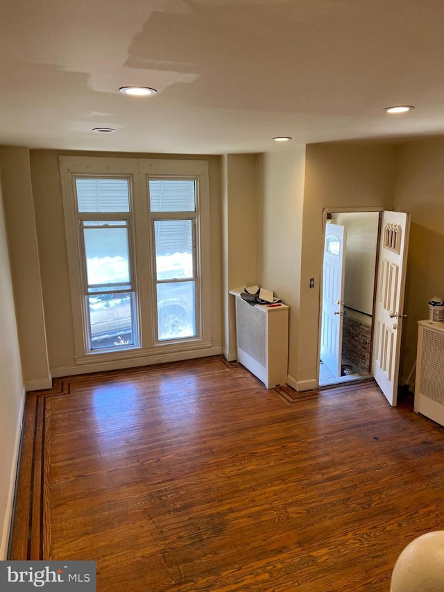 empty room featuring dark hardwood / wood-style floors and radiator