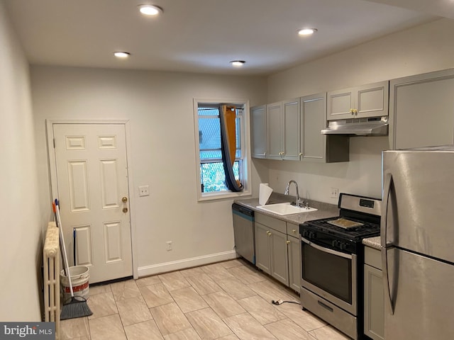 kitchen featuring radiator heating unit, gray cabinetry, sink, and appliances with stainless steel finishes