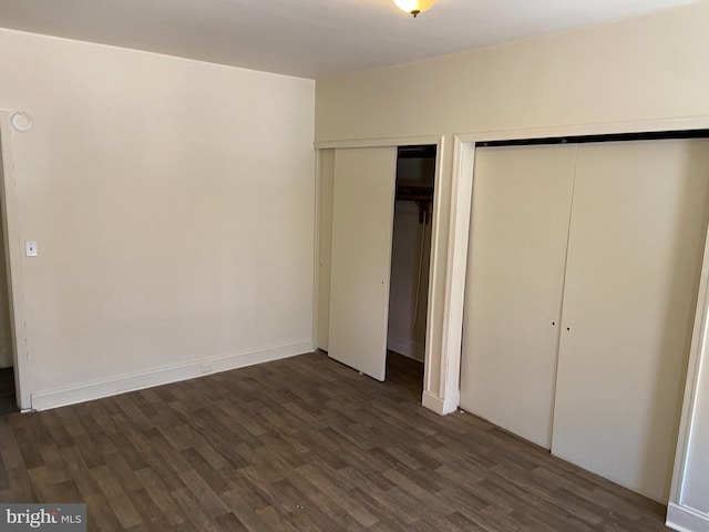 unfurnished bedroom with dark wood-type flooring and multiple closets