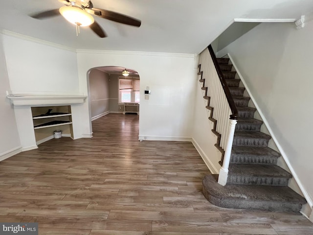 unfurnished living room featuring wood-type flooring, ceiling fan, and crown molding