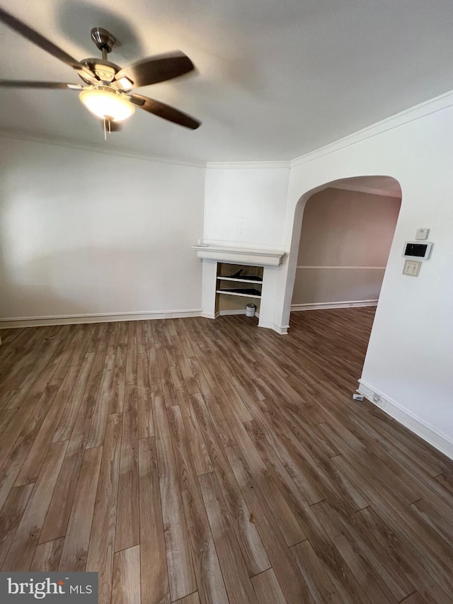 unfurnished living room featuring dark wood-type flooring, ornamental molding, and ceiling fan