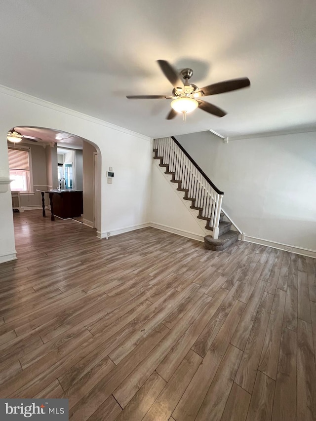 unfurnished living room with ornamental molding, sink, wood-type flooring, and ceiling fan