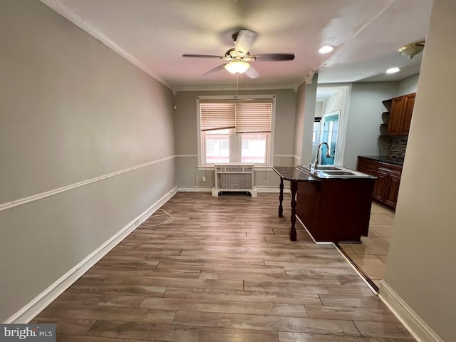 kitchen with crown molding, light hardwood / wood-style flooring, ceiling fan, a kitchen bar, and sink