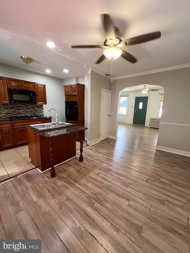 kitchen with black appliances, ceiling fan, light wood-type flooring, sink, and backsplash