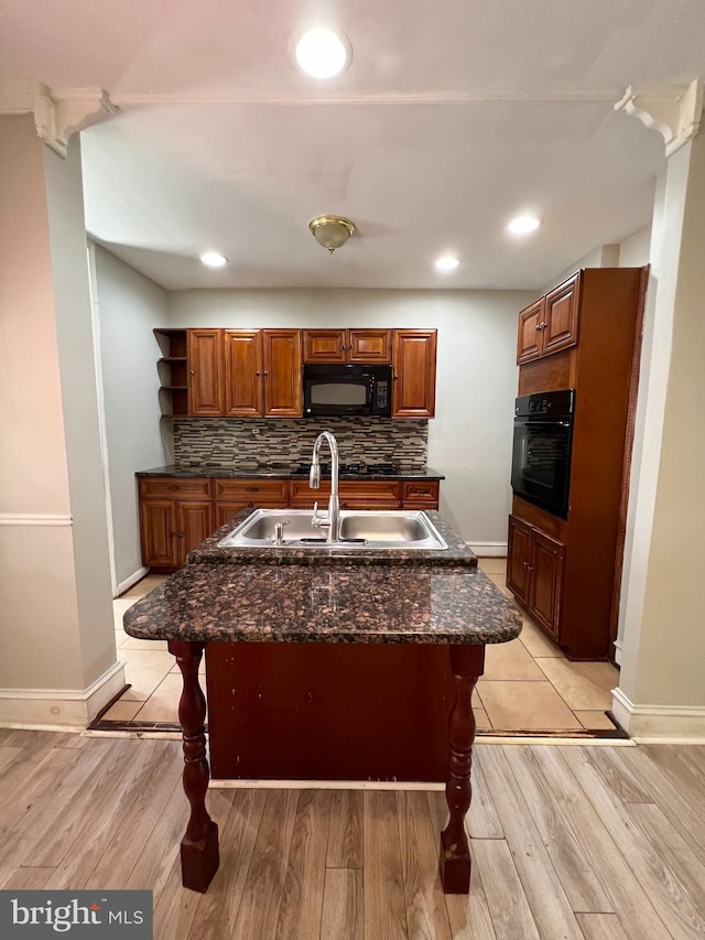 kitchen featuring decorative backsplash, a kitchen breakfast bar, black appliances, and light hardwood / wood-style floors