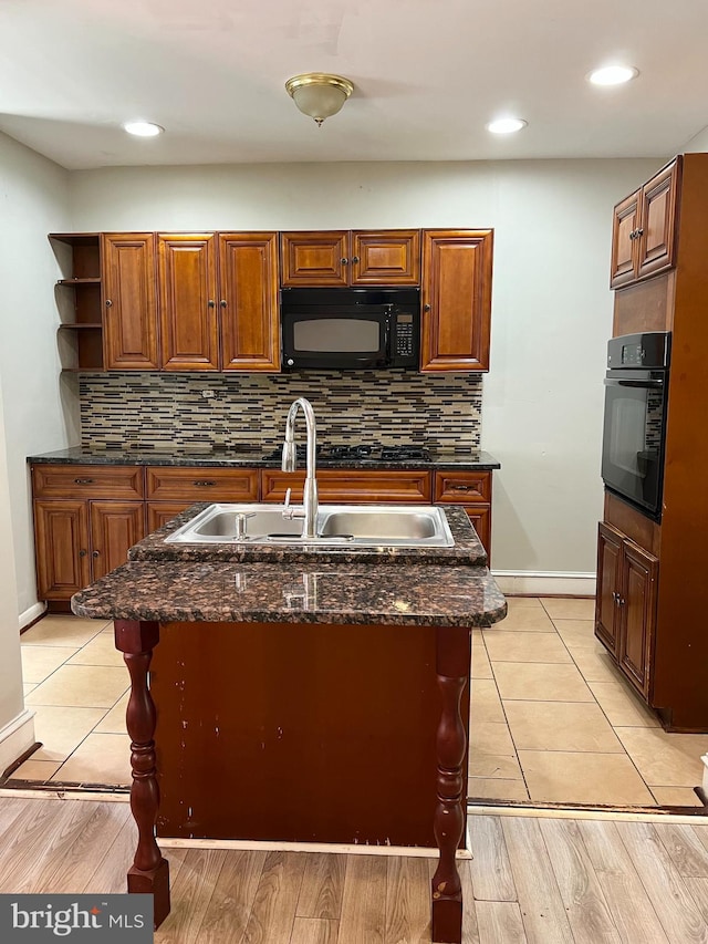 kitchen with black appliances, sink, and light wood-type flooring