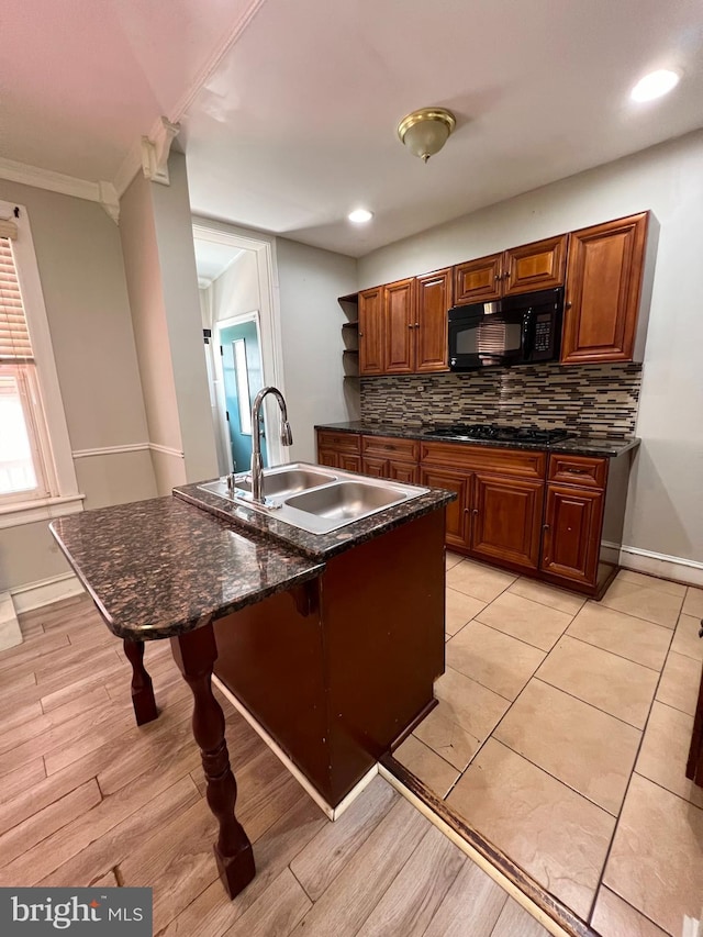 kitchen with black appliances, ornamental molding, sink, dark stone countertops, and backsplash