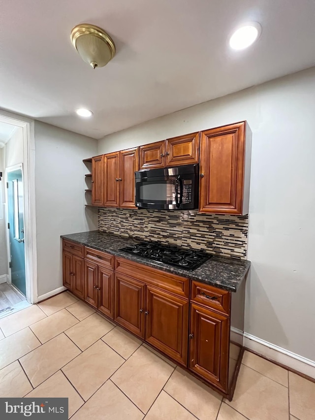 kitchen featuring light tile patterned flooring, backsplash, black appliances, and dark stone counters