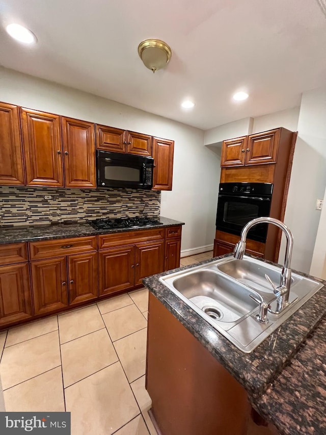 kitchen with dark stone counters, tasteful backsplash, black appliances, sink, and light tile patterned floors